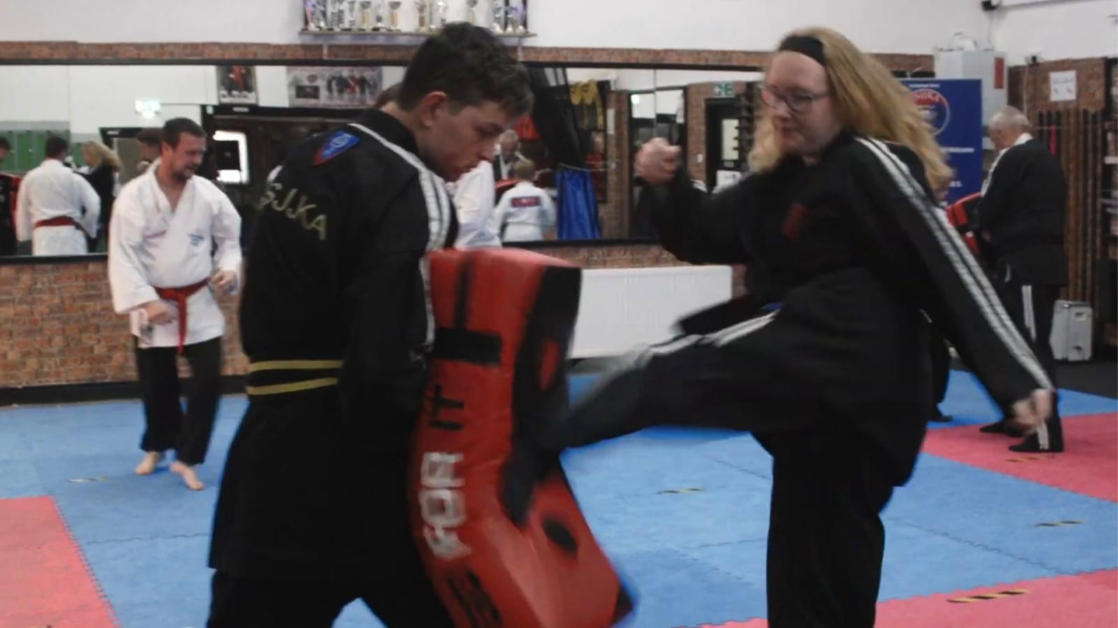 Female Ju Jitsu student kicking a pad.